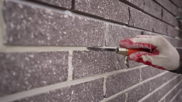 Worker Wipes the Seams in the Brickwork