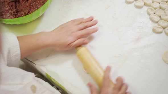 Female Hands Roll Out Even Pieces of Dough with a Rolling Pin Which are Cut and Lie on the Table