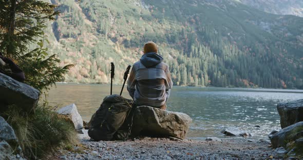 Male Hiker Backpacker Wearing Yellow Hat Plaid Shirt Resting Relaxing Sitting on Stone on Beautiful