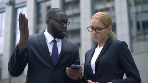 Businessman Telling Female Colleague About Useful Application on Smartphone