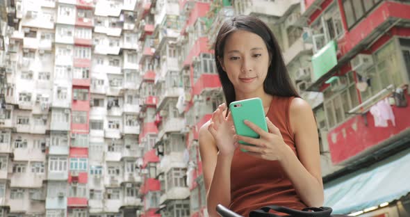 Woman using mobile phone in residential building in Hong Kong city