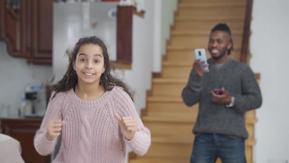 Medium Shot of Carefree Cheerful African American Teen Girl Having Fun Dancing in Living Room with