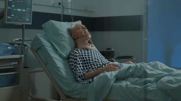 Old Patient with Cervical Neck Collar Laying in Hospital Ward