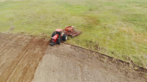 Farmer on a Tractor with a Sowing Unit Cultivates Fertile Farmland in the Spring