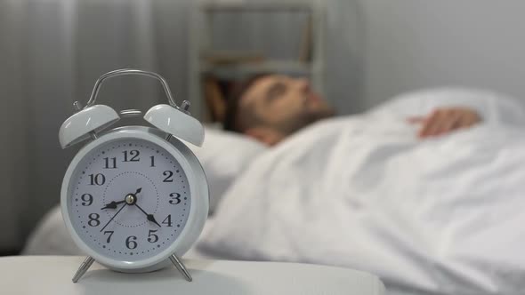 Man in Bed Waking Up to Ringing Alarm Clock