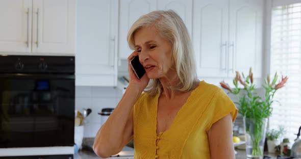 Senior Woman Talking on Mobile Phone in Kitchen 4k