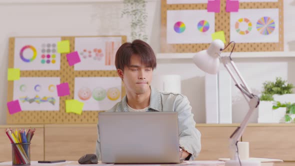 Smiling entrepreneur sitting at desk working on laptop