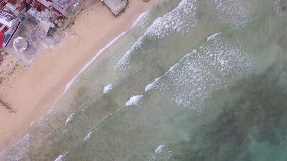 Bird's eye drone view flying the shallow shoreline waters to over the small rural town of Matutinao