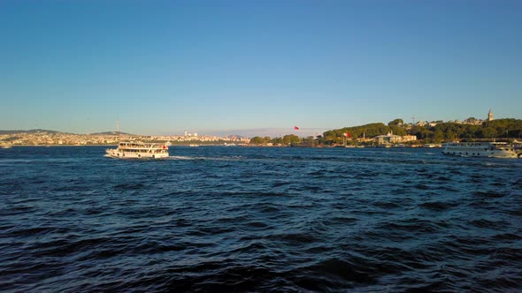 Cinematic close up view of waves of ocean. Out of focus view of the buildings and ships sailing on t