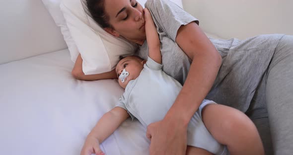 Young mother lying with her son on bed at home