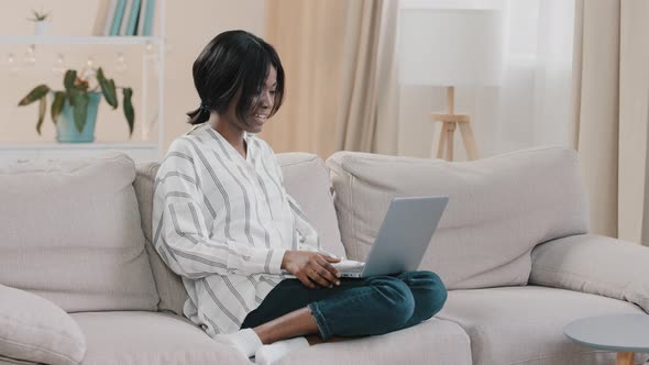 Young Woman Student Freelancer Sitting on Comfortable Couch in Cozy Room Chatting Via Video Call