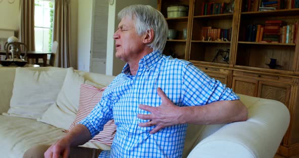 Senior man suffering from chest pain in living room