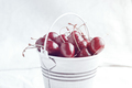 Small white bucket full of red cherries on a light background. Bright sunlight. - PhotoDune Item for Sale
