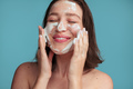 Delighted young lady with closed eyes applying foam cleanser on face - PhotoDune Item for Sale