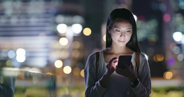 Woman send on cellphone in city at night