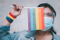 Asian lady wearing mask for protect covid19 virus holding rainbow flag, symbol of LGBT. - PhotoDune Item for Sale