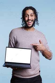laptop with white empty screen portrait. Smiling cheerful person pointing with finger at portable computer and looking at camera