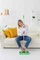 Smiling millennial woman housewife with mop for washes floor enjoys cleaning in minimalist interior - PhotoDune Item for Sale