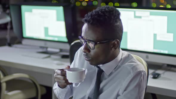 Office Worker Drinking Coffee in Office at Night