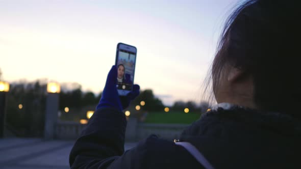 Close up happy Asian woman standing and taking video call in public Frogner park, Norway