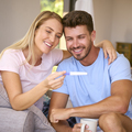 Excited Couple In Bedroom At Home Celebrating Positive Pregnancy Test Result - PhotoDune Item for Sale