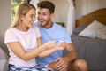 Excited Couple In Bedroom At Home Celebrating Positive Pregnancy Test Result - PhotoDune Item for Sale
