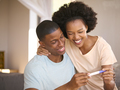 Excited Couple In Bedroom At Home Celebrating Positive Pregnancy Test Result - PhotoDune Item for Sale