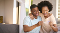 Excited Couple In Bedroom At Home Celebrating Positive Pregnancy Test Result - PhotoDune Item for Sale