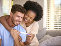 Excited Multi-Racial Couple In Bedroom At Home Celebrating Positive Pregnancy Test Result - PhotoDune Item for Sale