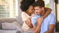 Excited Multi-Racial Couple In Bedroom At Home Celebrating Positive Pregnancy Test Result - PhotoDune Item for Sale