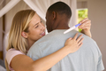 Hugging Multi-Racial Couple In Bedroom At Home Celebrating Positive Pregnancy Test Result - PhotoDune Item for Sale