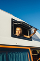 The happy girl sticks her head out of the van window on a wonderful day at camp. Van life concept. - PhotoDune Item for Sale