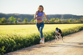 Beautiful young blonde woman running in the field with her greyhound dog. - PhotoDune Item for Sale