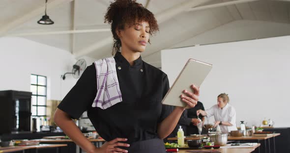 Mixed race female chef using digital tablet