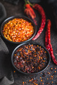 Smoked dry chili pepper flakes. Crushed red peppers in bowl on black table. - PhotoDune Item for Sale