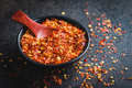 Dry chili pepper flakes. Crushed red peppers in bowl on black table. - PhotoDune Item for Sale