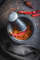 Dry chili pepper flakes. Crushed red peppers in mortar on black table. Top view. - PhotoDune Item for Sale