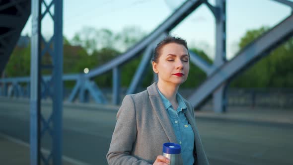 Caucasian Businesswoman in a Coat Walking Around the City in the Early Morning Drinking Coffee Slow