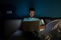 African American guy freelance lying in bed using laptop working remotely until late hours - PhotoDune Item for Sale