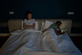 Indifferent man husband using smartphone, ignoring sad unhappy wife while lying together in bed - PhotoDune Item for Sale