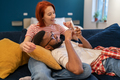 Multi ethnic happy couple man and woman look at phone lying on couch in living room. - PhotoDune Item for Sale