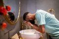 African American millennial guy cleaning skin in morning, washing face with water in bathroom - PhotoDune Item for Sale
