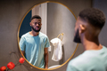 Unhappy African American man looking in mirror in bathroom, feeling dissatisfied with his appearance - PhotoDune Item for Sale