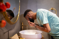 African American millennial guy cleaning skin in morning, washing face with water in bathroom - PhotoDune Item for Sale