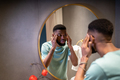 Worried african american man looks at mirror, touches facial skin anxious about wrinkles. - PhotoDune Item for Sale