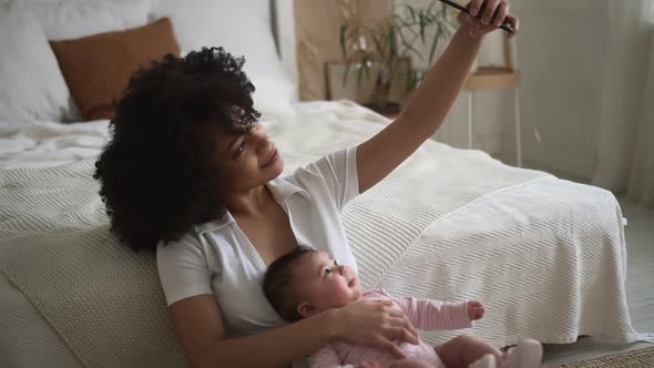 Mom Taking Selfie Photo with Baby Girl and Sitting in Bright Home Bedroom Spbd