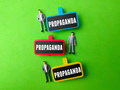 Miniature people and wooden board with the word PROPAGANDA on green background. - PhotoDune Item for Sale
