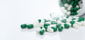 Green and white capsule pill spread out of pill bottle. Healthcare and medicine. Prescription drug. - PhotoDune Item for Sale