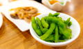 Edamame or green soybeans blanched in white bowl on wooden table at Japanese restaurant. Pods - PhotoDune Item for Sale