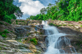 Beautiful waterfall at the mountain with blue sky and white cumulus clouds. Waterfall in tropical - PhotoDune Item for Sale